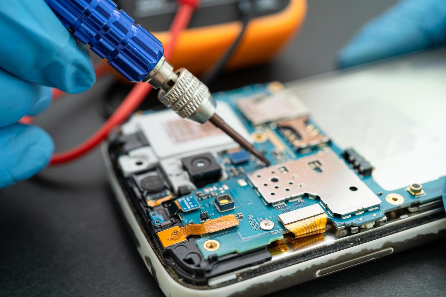 technicien réparant l'intérieur du téléphone portable en fer à souder. circuit intégré. le concept de données, de matériel, de technologie. photo