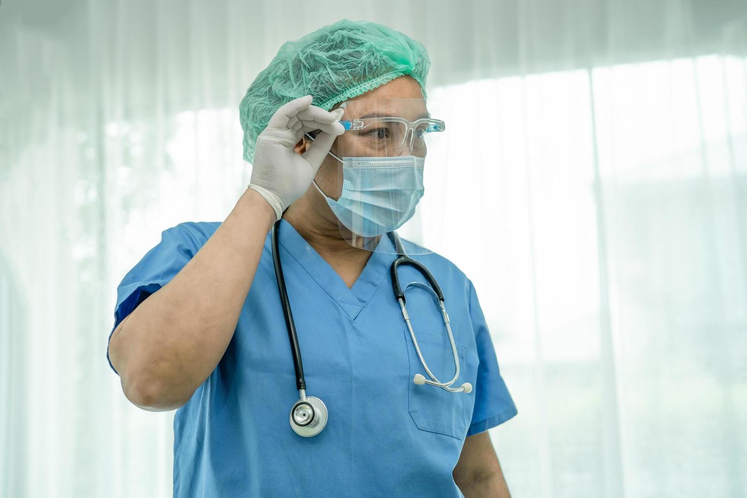 médecin asiatique portant un écran facial et un costume d'EPI nouvelle norme pour vérifier que le patient protège l'infection de sécurité covid 19 épidémie de coronavirus dans la salle d'hôpital de quarantaine. photo