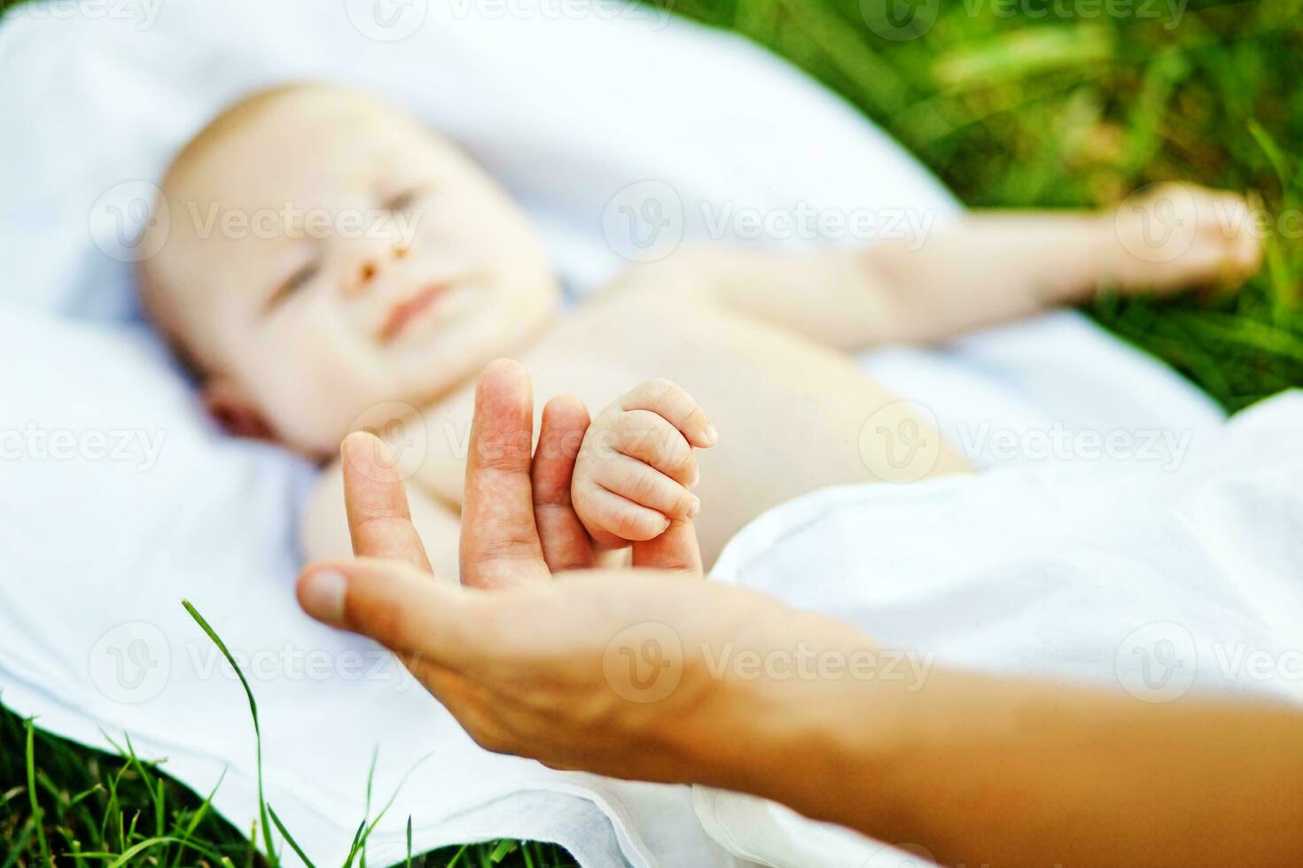 une bébé pose sur une couverture avec une main atteindre en dehors photo