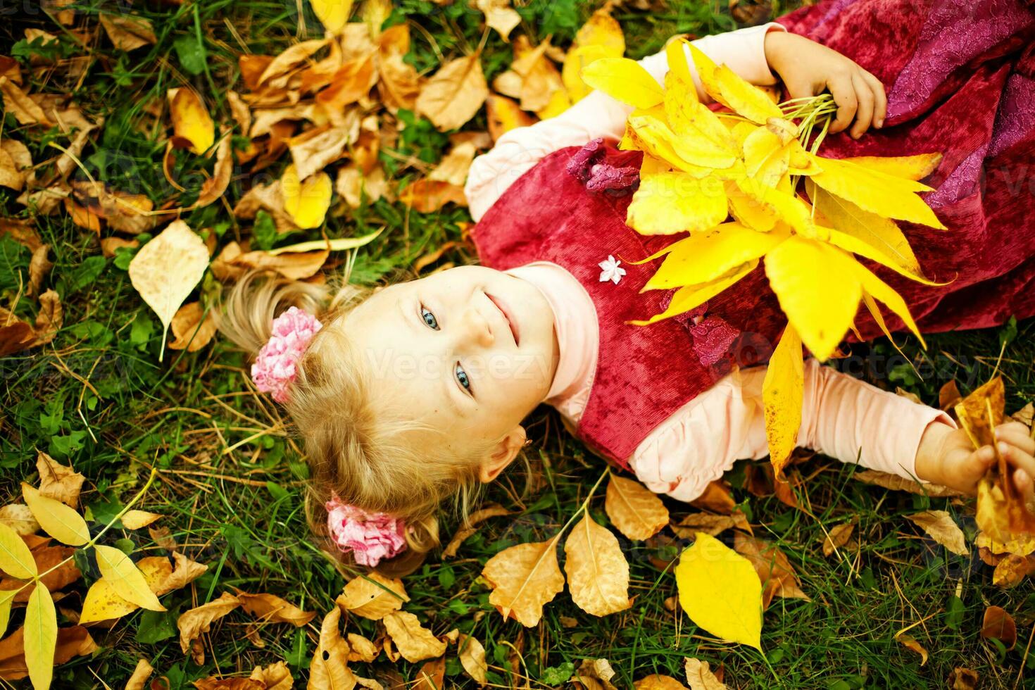 une peu fille pose sur le sol avec feuilles photo