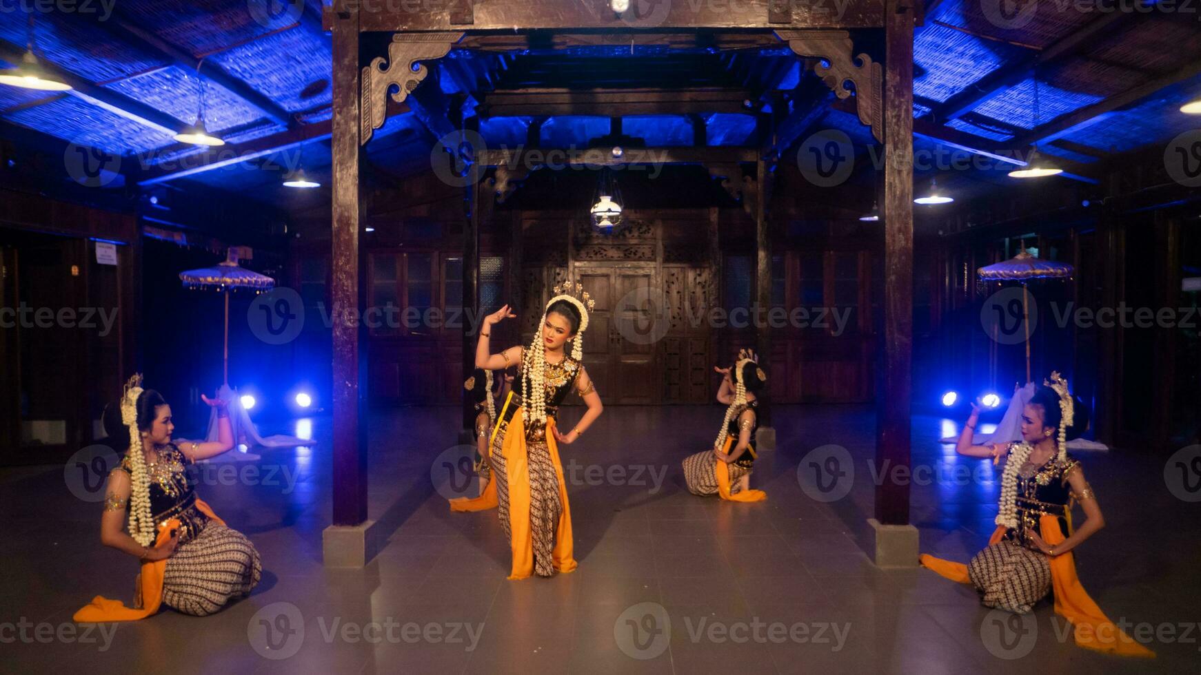 une groupe de sundanais danseurs dans Jaune costumes Danse une traditionnel Danse dans de face de une bleu lumière photo