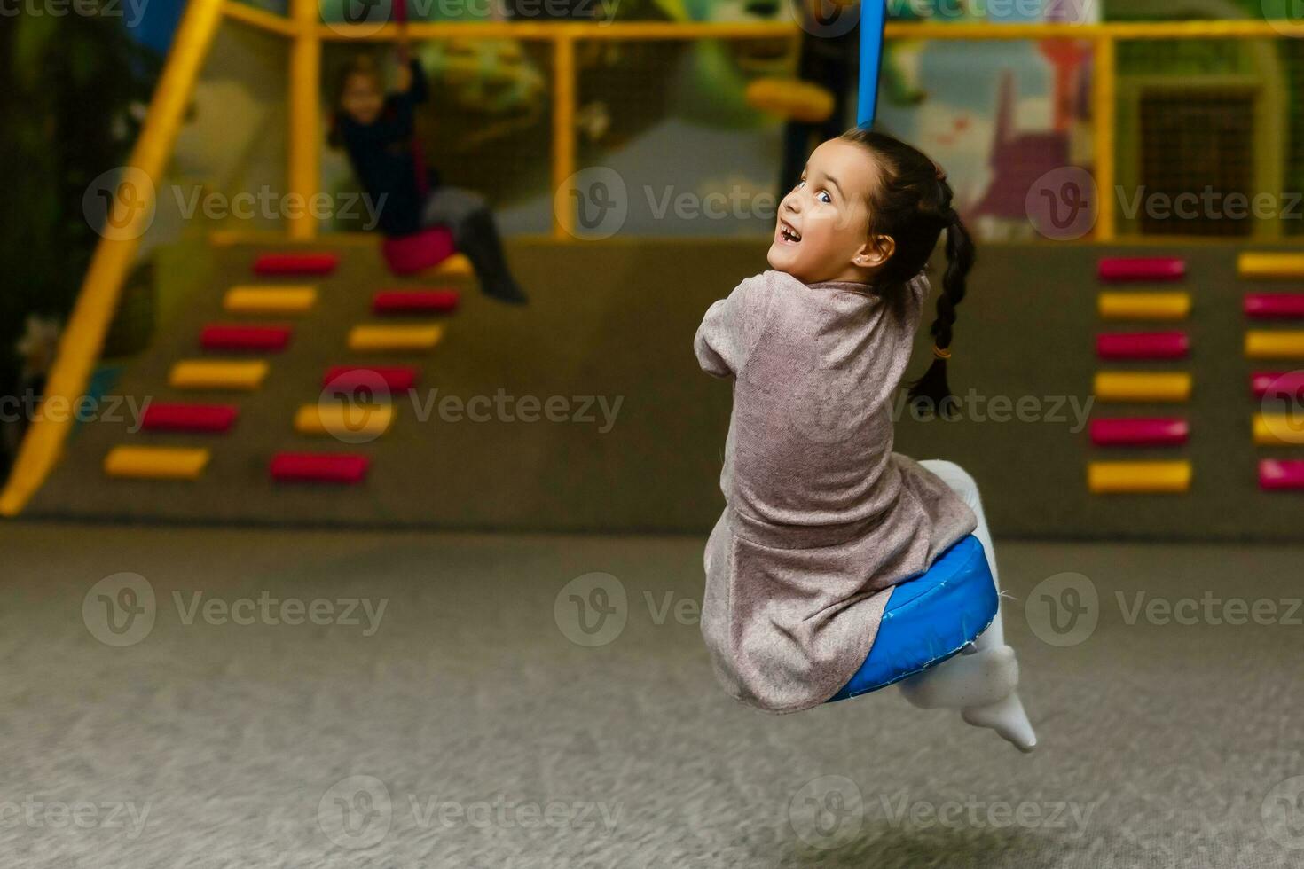 mignonne peu fille est en jouant sur le Cour de récréation. le fille est équitation sur une balançoire. photo