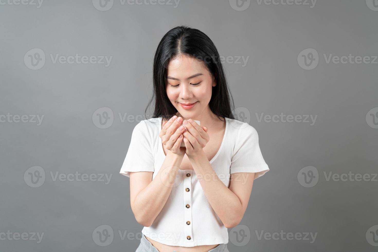 jeune femme asiatique avec un visage heureux et une main tenant une tasse de café photo