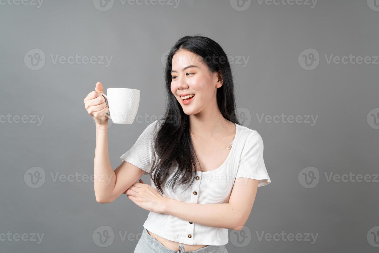 jeune femme asiatique avec un visage heureux et une main tenant une tasse de café photo