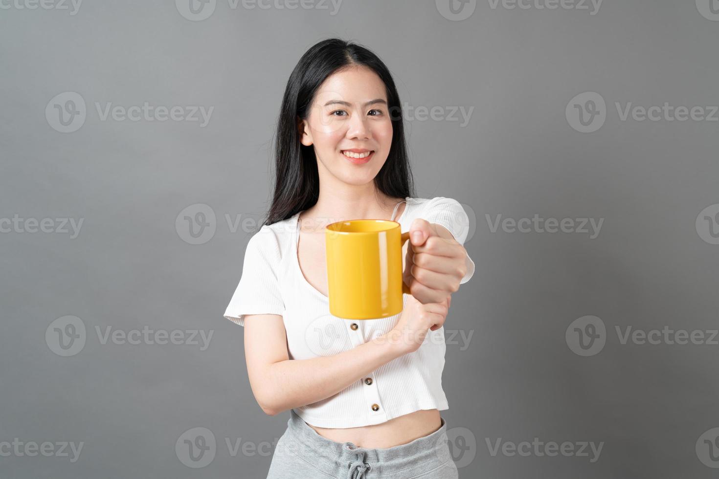 jeune femme asiatique avec un visage heureux et une main tenant une tasse de café photo