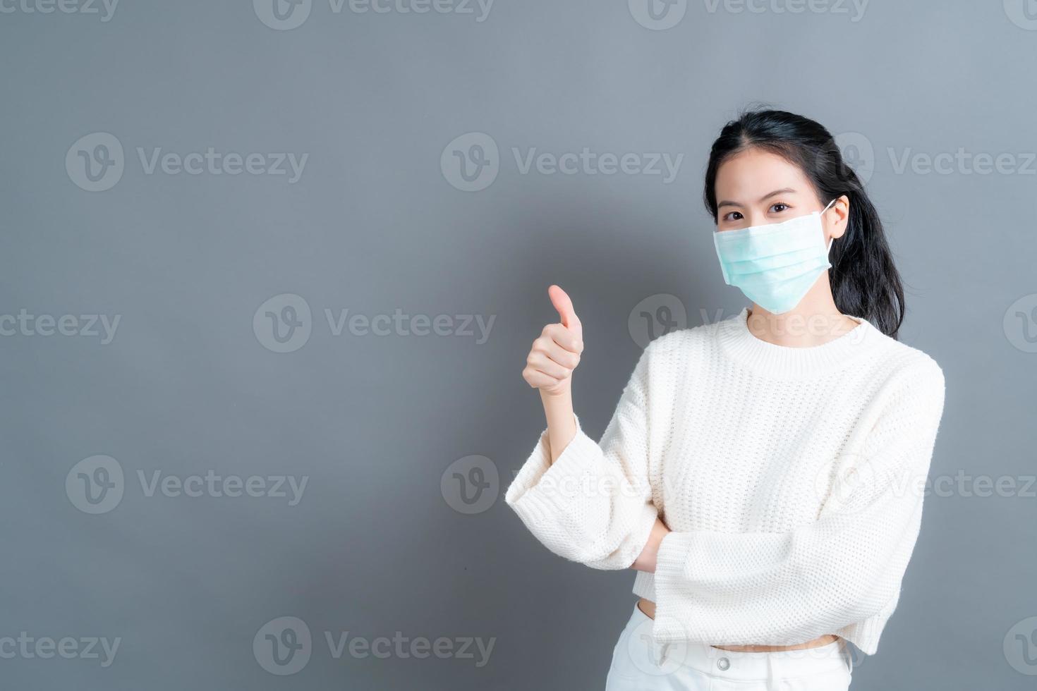 jeune femme asiatique portant un masque médical et levant les pouces photo