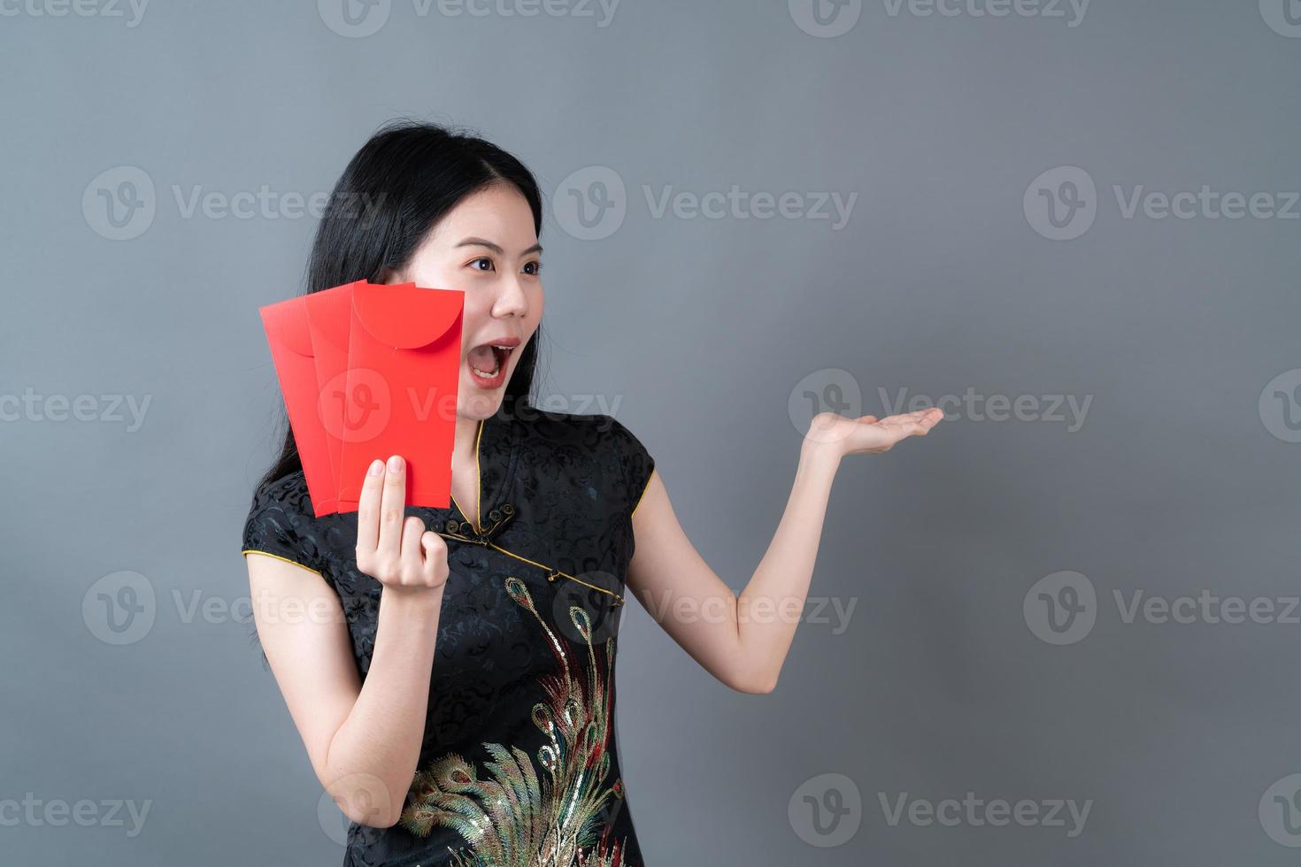 une femme asiatique porte une robe traditionnelle chinoise avec une enveloppe rouge ou un paquet rouge photo