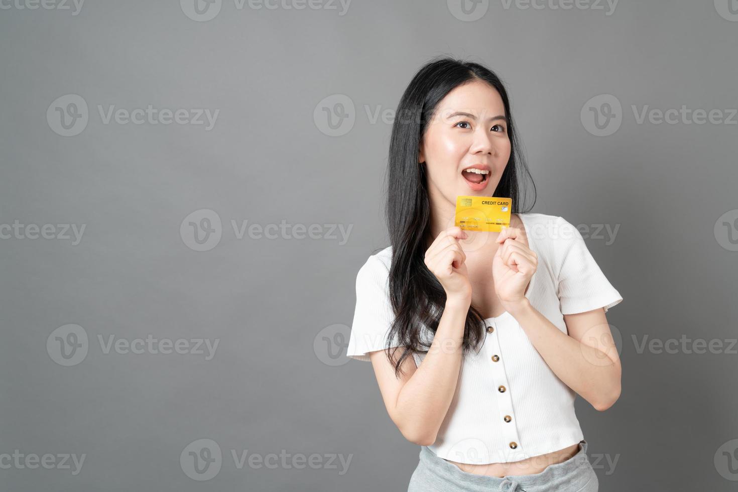 femme asiatique avec un visage heureux et présentant une carte de crédit en main montrant la confiance pour effectuer le paiement photo