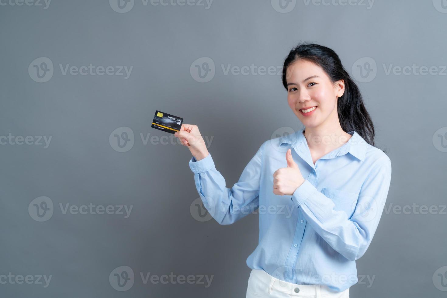 portrait d'une jolie jeune femme asiatique montrant une carte de crédit photo