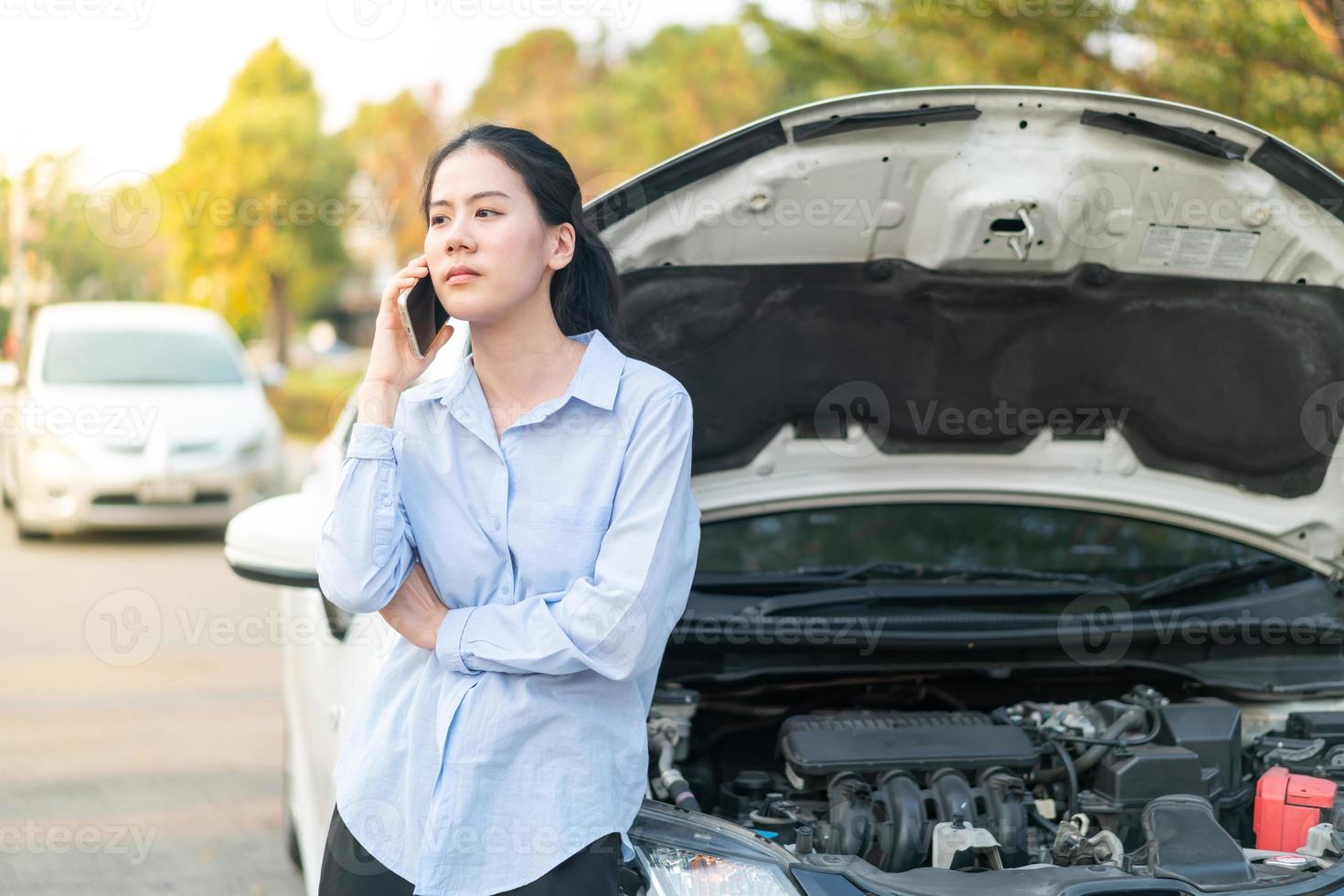 Jeune femme debout près d'une voiture en panne avec un capot qui a des problèmes avec son véhicule photo