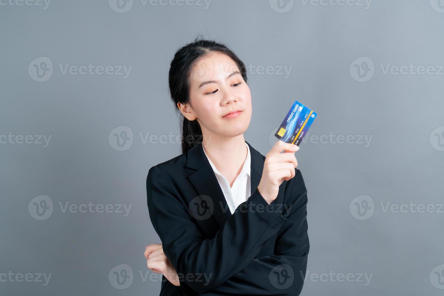 portrait d'une jolie jeune femme asiatique montrant une carte de crédit photo