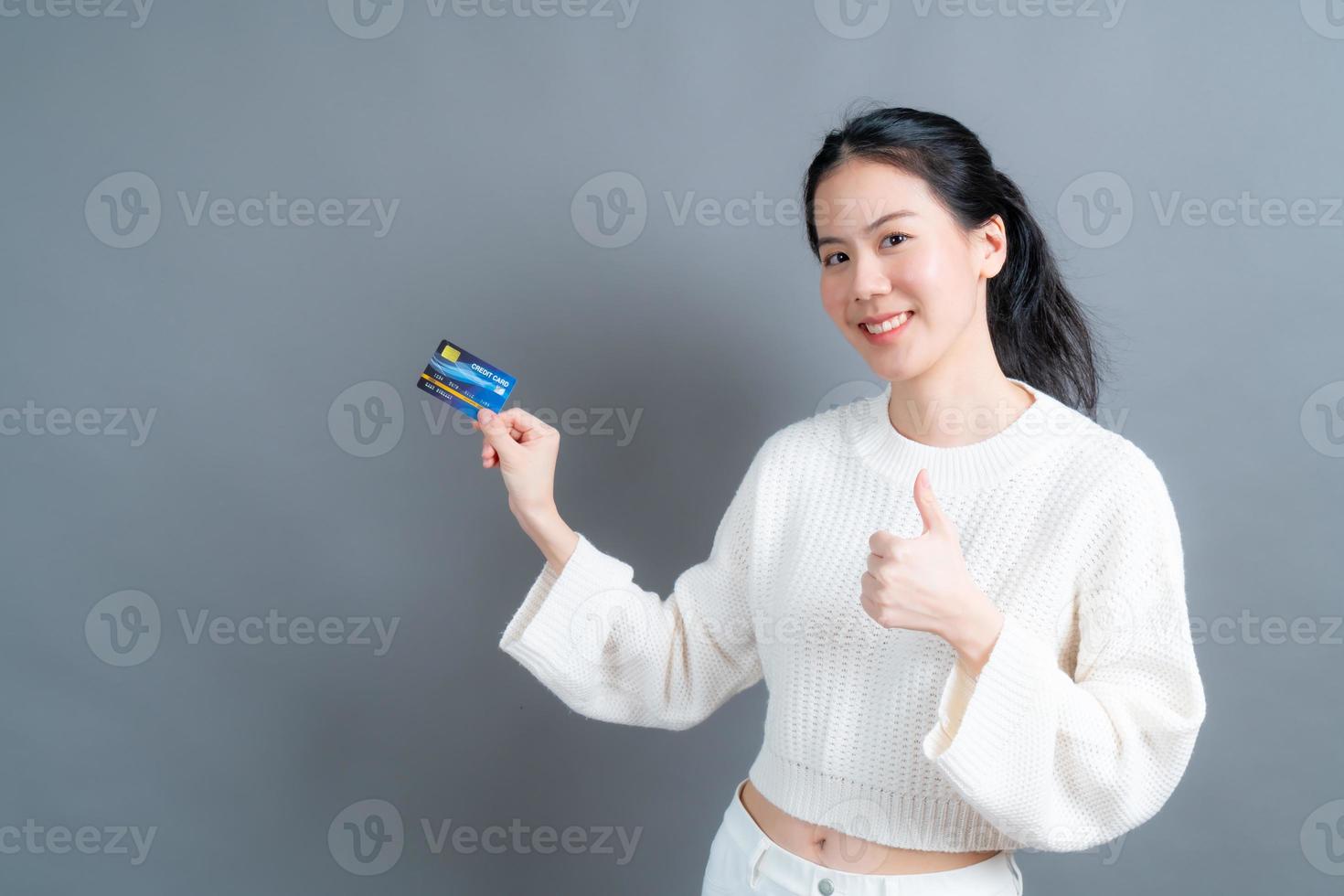 portrait d'une jolie jeune femme asiatique en pull montrant une carte de crédit avec espace de copie photo