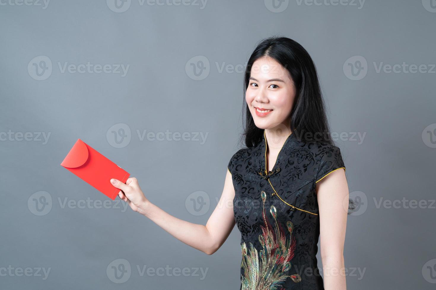 une femme asiatique porte une robe traditionnelle chinoise avec une enveloppe rouge ou un paquet rouge photo