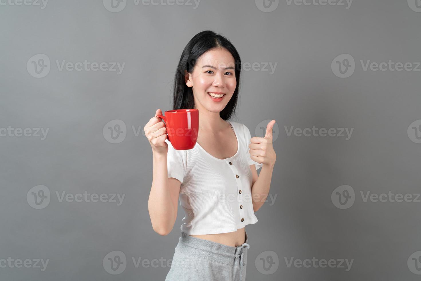 jeune femme asiatique avec un visage heureux et une main tenant une tasse de café photo