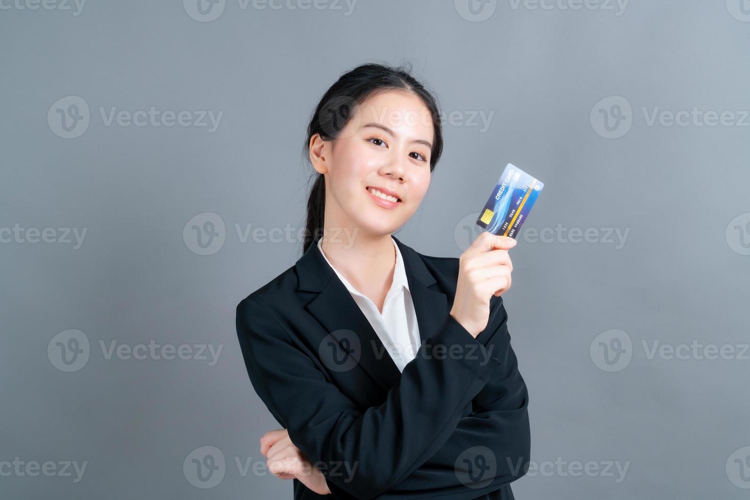 portrait d'une jolie jeune femme asiatique montrant une carte de crédit photo