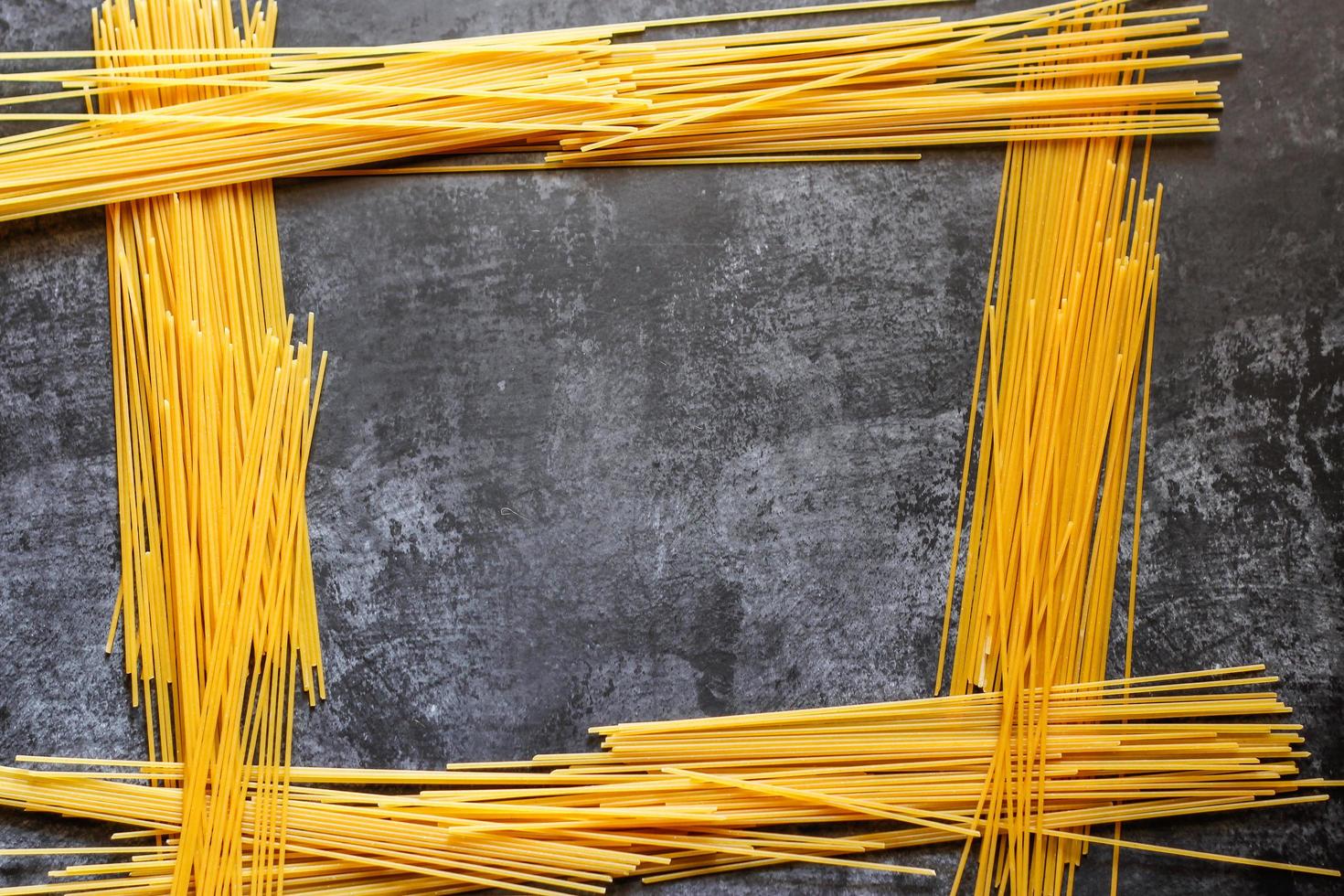 longs spaghettis jaunes sur fond rustique. pâtes italiennes jaunes. longs spaghettis. spaghettis crus à la bolognaise. spaghettis crus. concept de fond de nourriture. concept de cuisine et de menu italien. photo