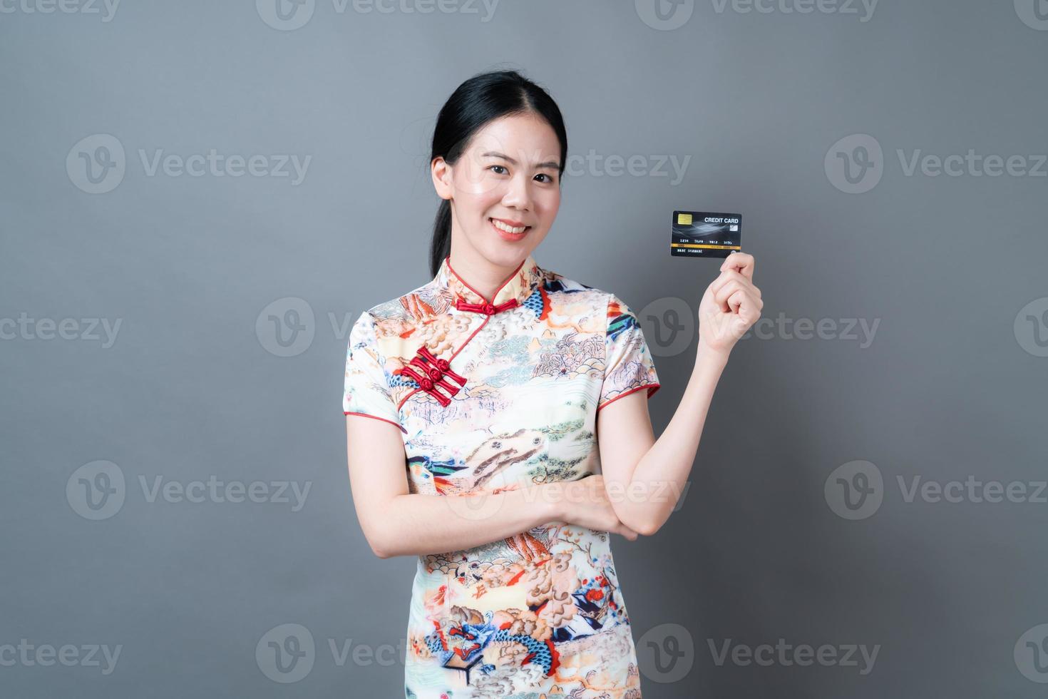 une femme asiatique porte une robe traditionnelle chinoise avec une main tenant une carte de crédit photo