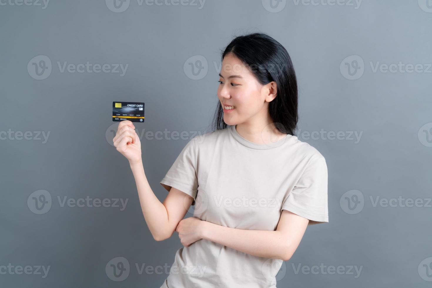 portrait d'une jolie jeune femme asiatique montrant une carte de crédit photo