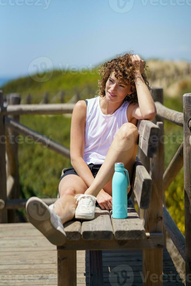 Jeune femme séance sur en bois banc sur pont photo