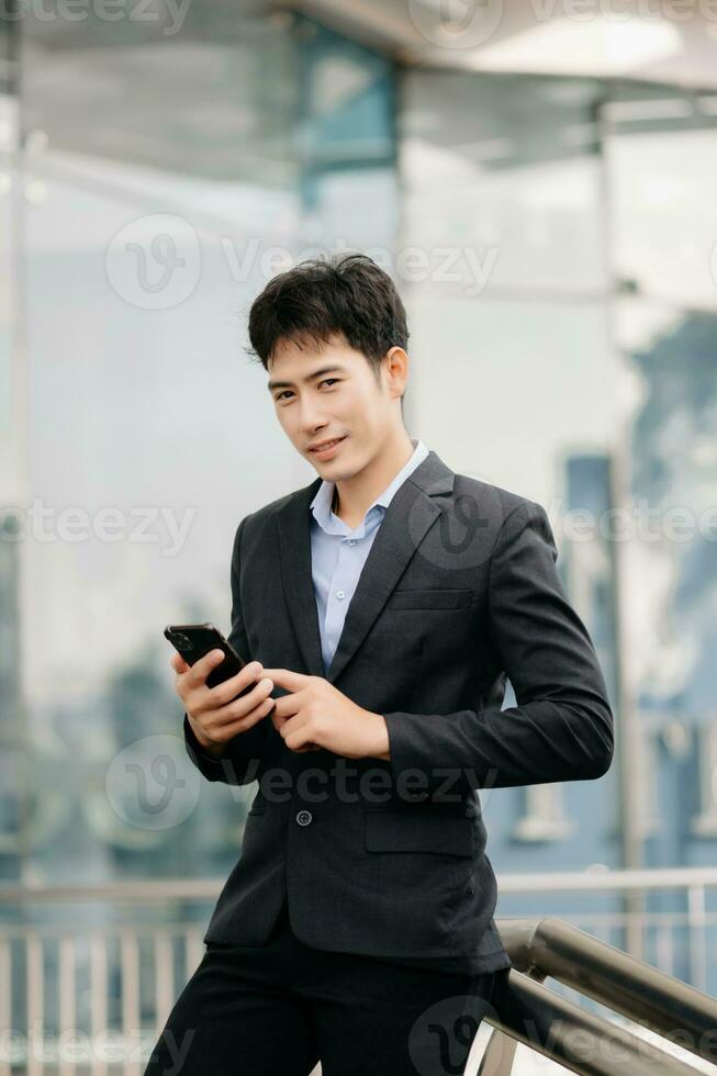 Jeune asiatique affaires homme travail à à l'extérieur affaires centre avec ordinateur portable, tablette, téléphone intelligent et prise Remarques sur le papier. photo