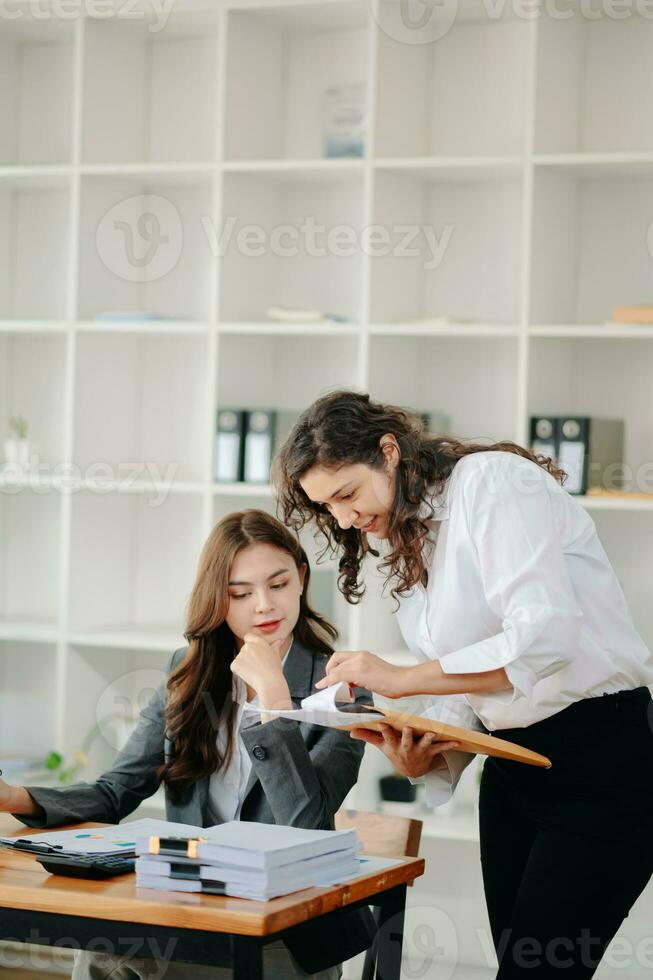 les femmes d'affaires travaillent et discutent de leurs plans d'affaires. une employée humaine explique et montre à sa collègue le document de résultats dans un bureau moderne. photo