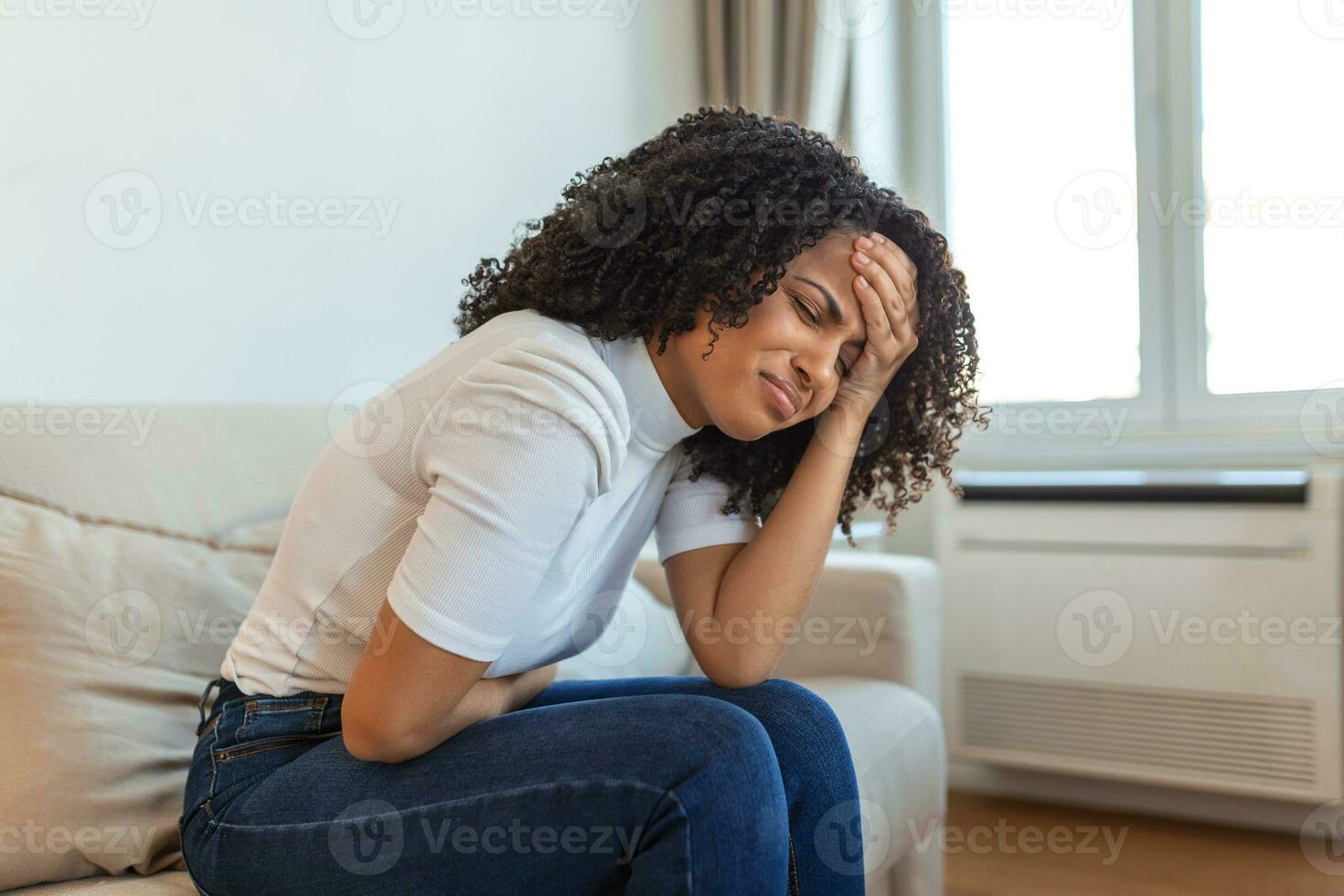 femme dans une expression douloureuse se tenant la main contre le ventre souffrant de douleurs menstruelles, allongée triste sur son lit à la maison, ayant une crampe abdominale dans le concept de santé féminine photo