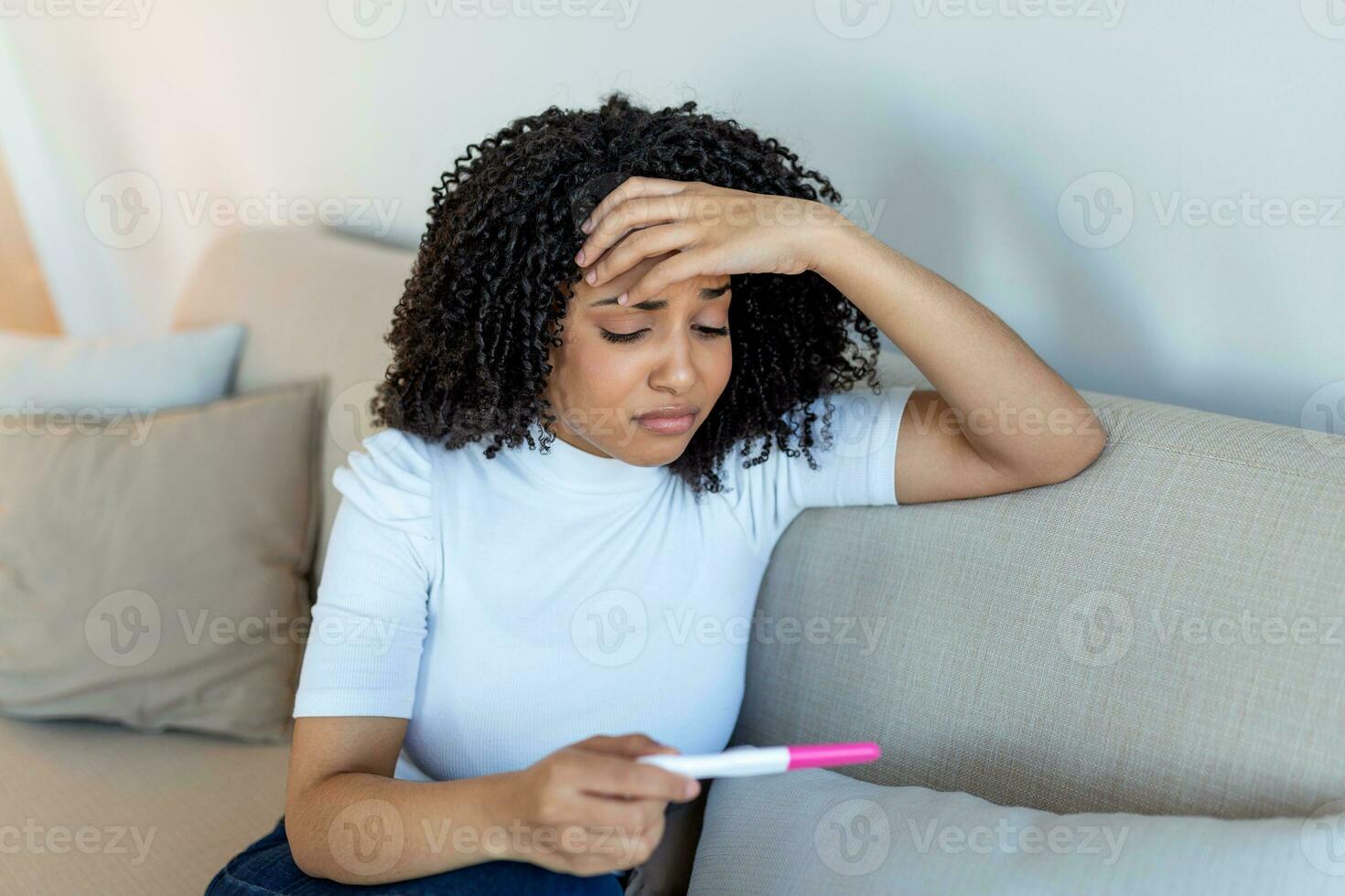 triste, inquiet africain américain femme vérification sa récent grossesse test, séance sur canapé à maison. maternité, enfant naissance et famille problèmes concept. indésirable grossesse photo