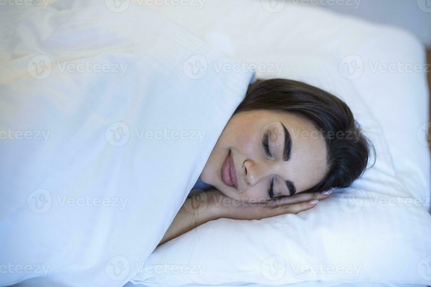 en bonne santé longue rêve, confortable lit avec blanc lin et orthopédique matelas. Jeune caucasien femme en train de dormir dans le lit, détendu calme rêves photo