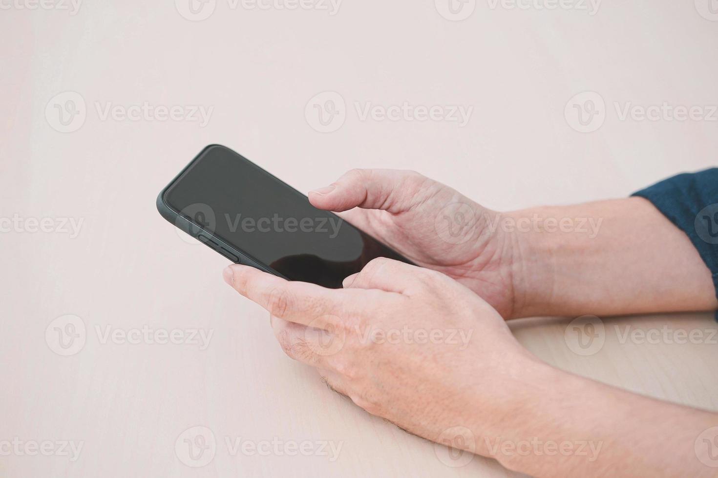 gros plan d'un homme utilisant un téléphone intelligent mobile sur une table en bois. photo