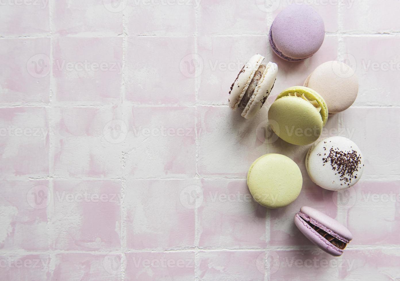 macarons colorés disposés sur fond de carreaux roses. photo