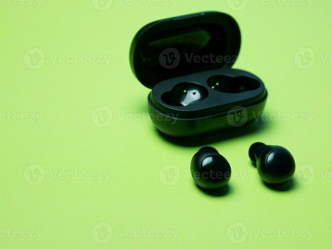 noir sans fil écouteurs avec le mise en charge Cas sur une vert Contexte. photo