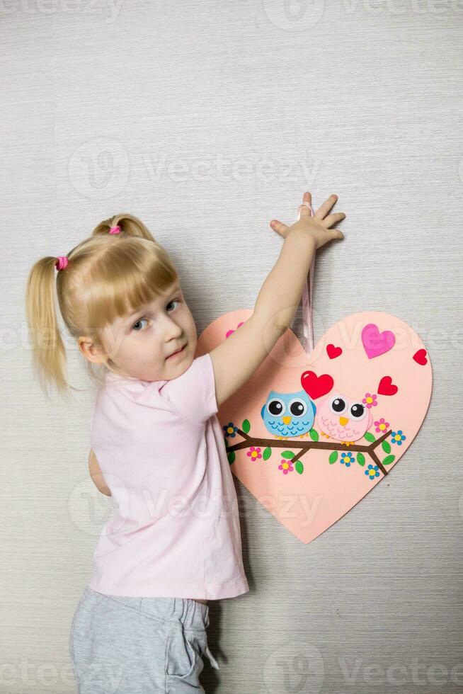 une blogueur fille fait du une se sentait artisanat pour la Saint-Valentin journée dans le forme de une cœur. le concept de enfants la créativité et Fait main. photo