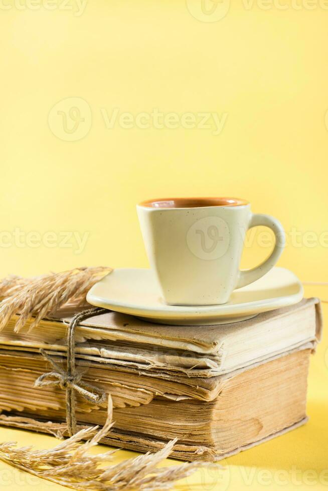 une tasse de café sur vieux livres et sec oreilles de blé dans Jaune. bien-être, harmonie, silencieux en lisant. copie espace, verticale vue photo