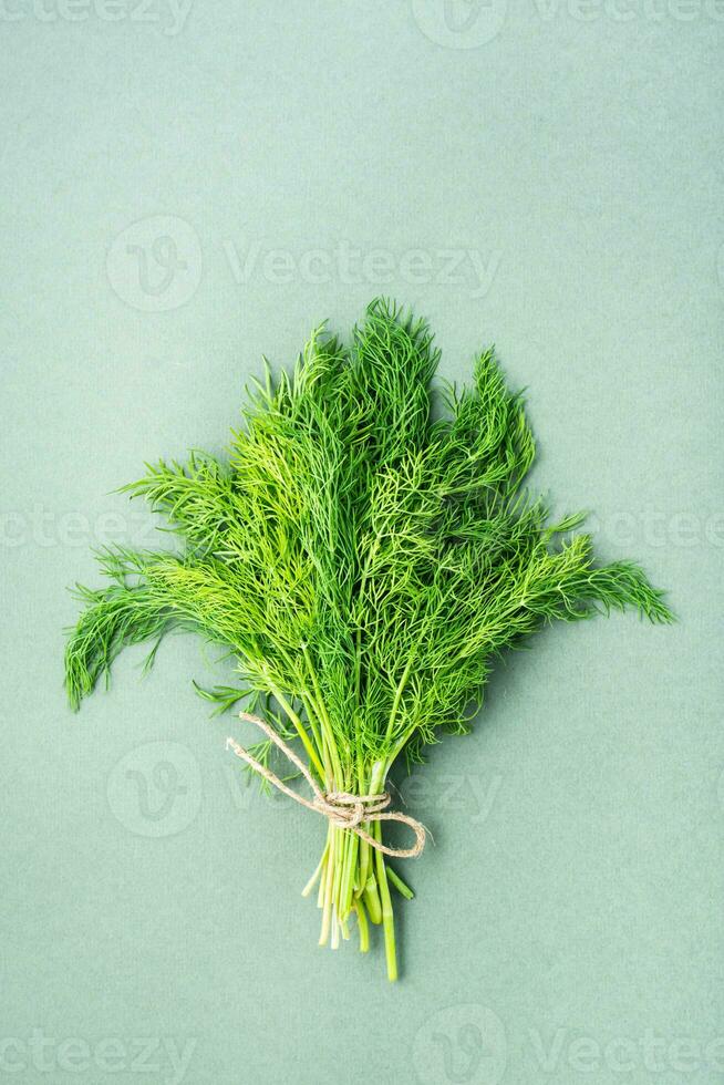 une bouquet de Frais aneth lié avec une corde sur une vert Contexte. vitamine légumes verts dans une en bonne santé régime. Haut et verticale vue photo