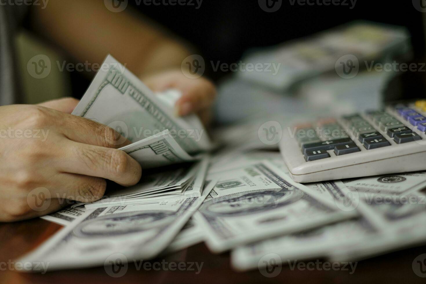hommes d'affaires femmes comptant de l'argent sur une pile de billets de 100 dollars américains photo
