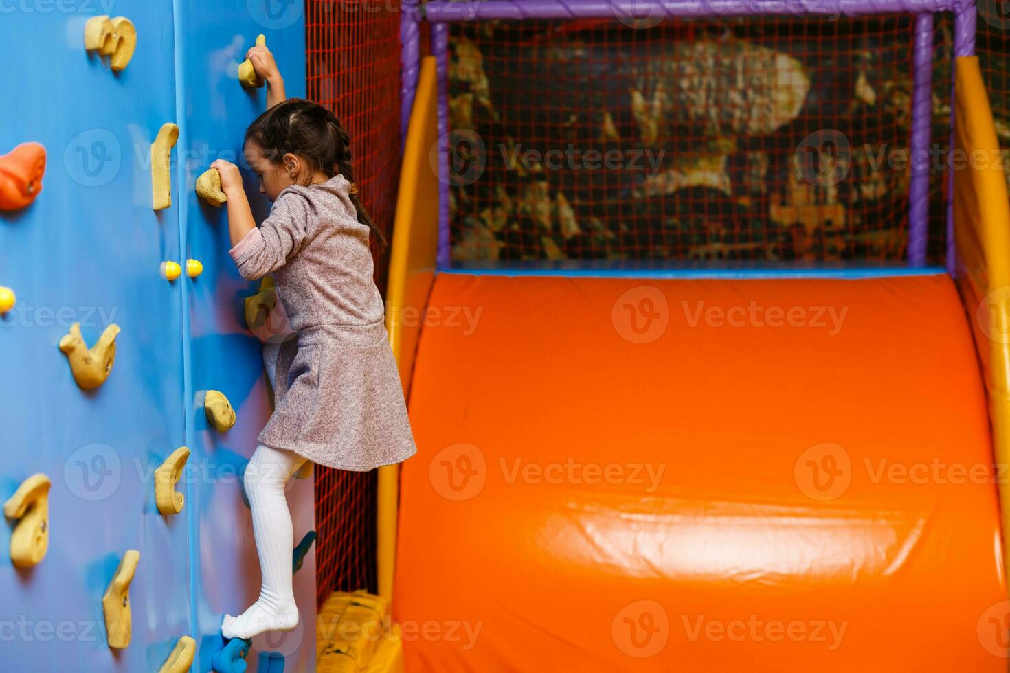 petite fille escaladant un mur de roche à l'intérieur photo