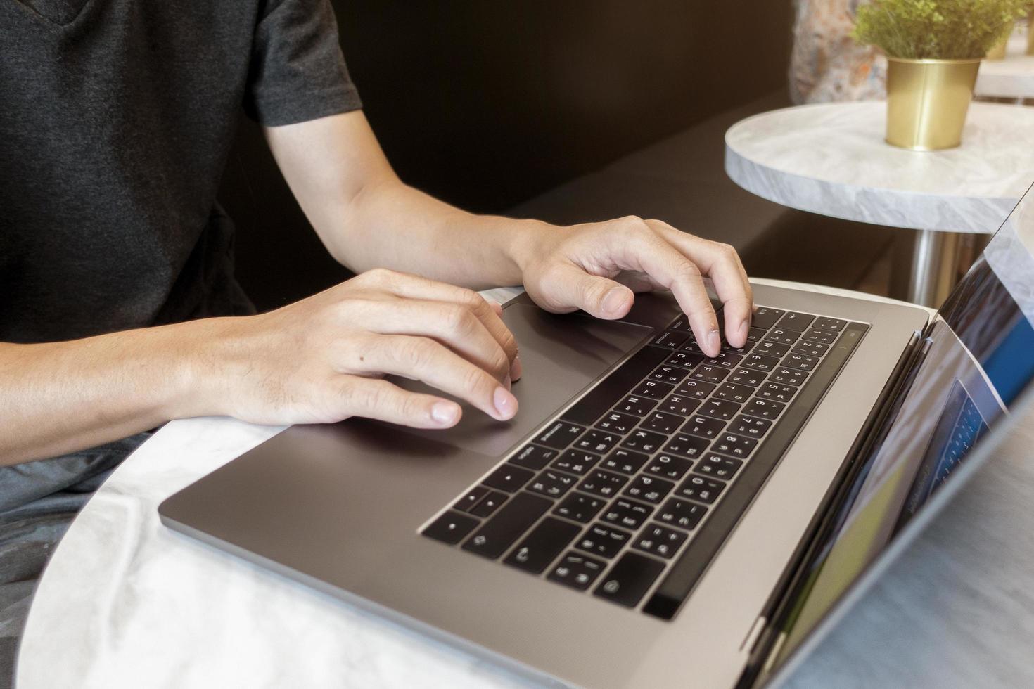 Close up man's hand working on laptop in coffee shop photo