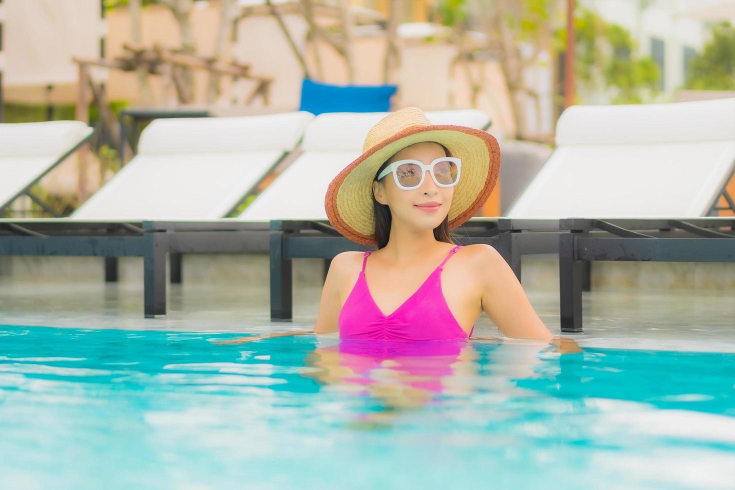 Portrait belle jeune femme asiatique se détendre sourire autour de la piscine extérieure de l'hôtel resort photo