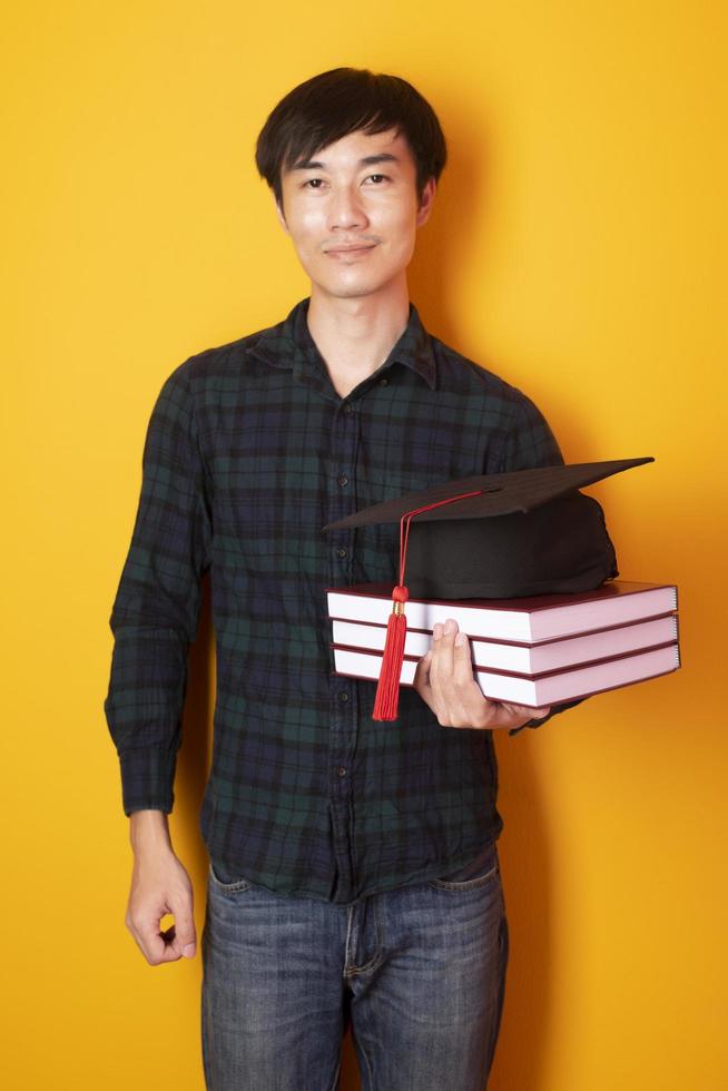 l'homme de l'université est heureux avec l'obtention du diplôme sur fond jaune photo