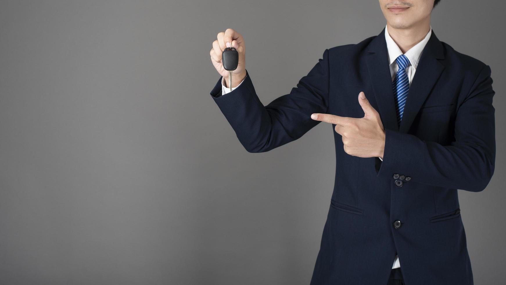 homme d'affaires tient la clé de voiture, fond gris en studio photo