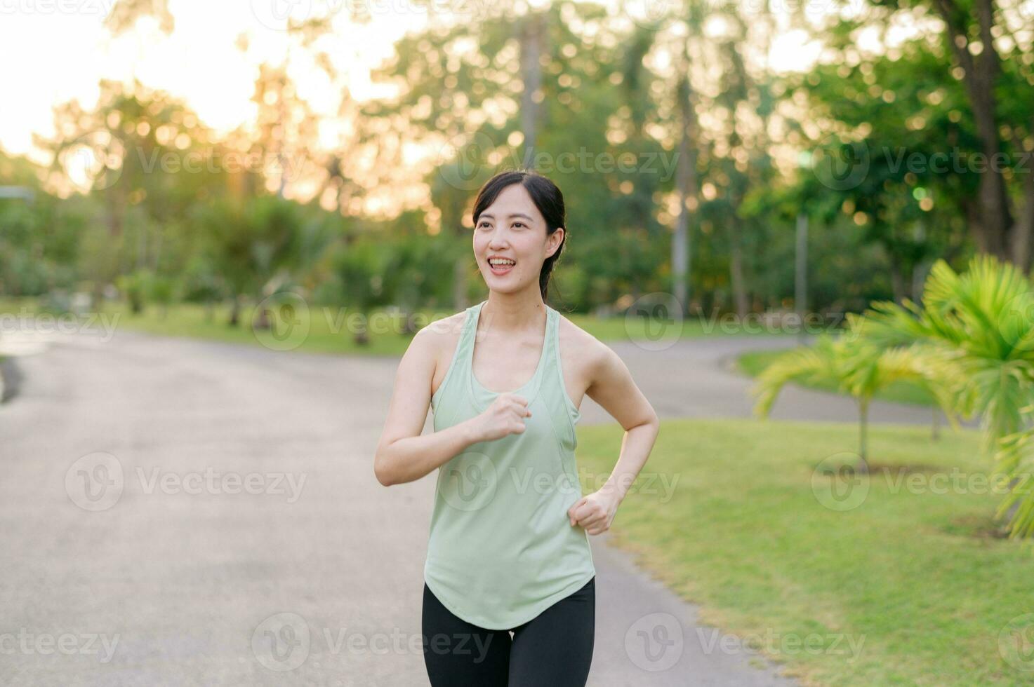 en forme asiatique Jeune femme le jogging dans parc souriant content fonctionnement et profiter une en bonne santé Extérieur mode de vie. femelle joggeur. aptitude coureur fille dans Publique parc. en bonne santé mode de vie et bien-être étant concept photo