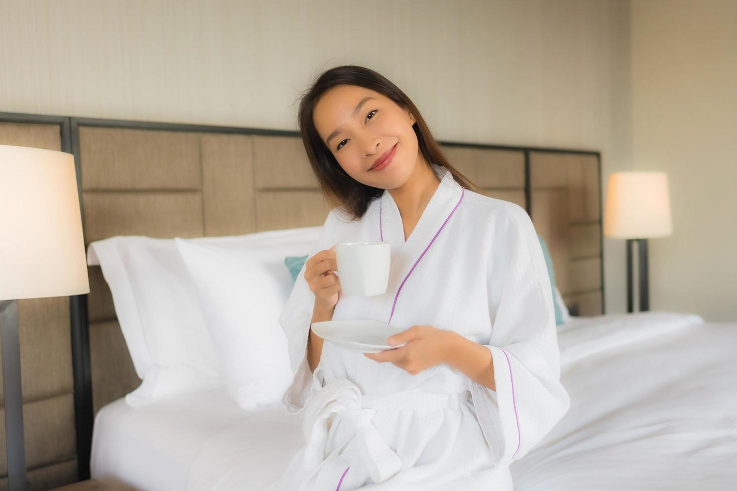 Portrait de belles jeunes femmes asiatiques avec une tasse de café sur le lit photo