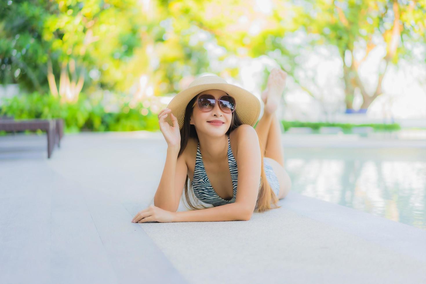 belles jeunes femmes asiatiques sourire heureux se détendre autour d'une piscine extérieure dans un complexe hôtelier pour voyager en vacances photo