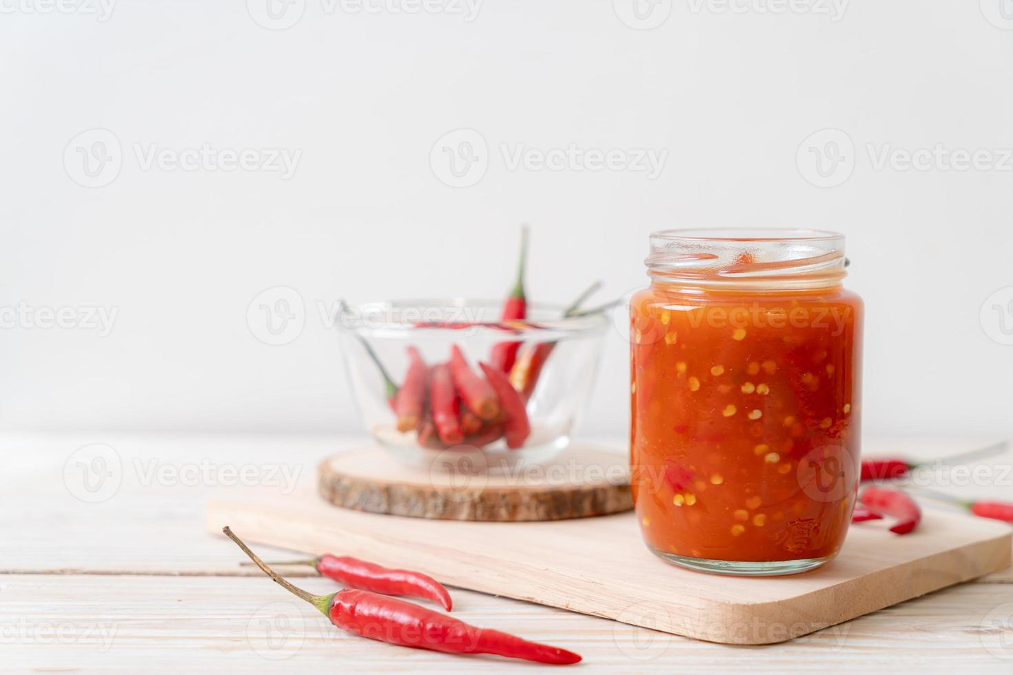 piment ou sauce chili en bouteille et pot sur fond de bois photo