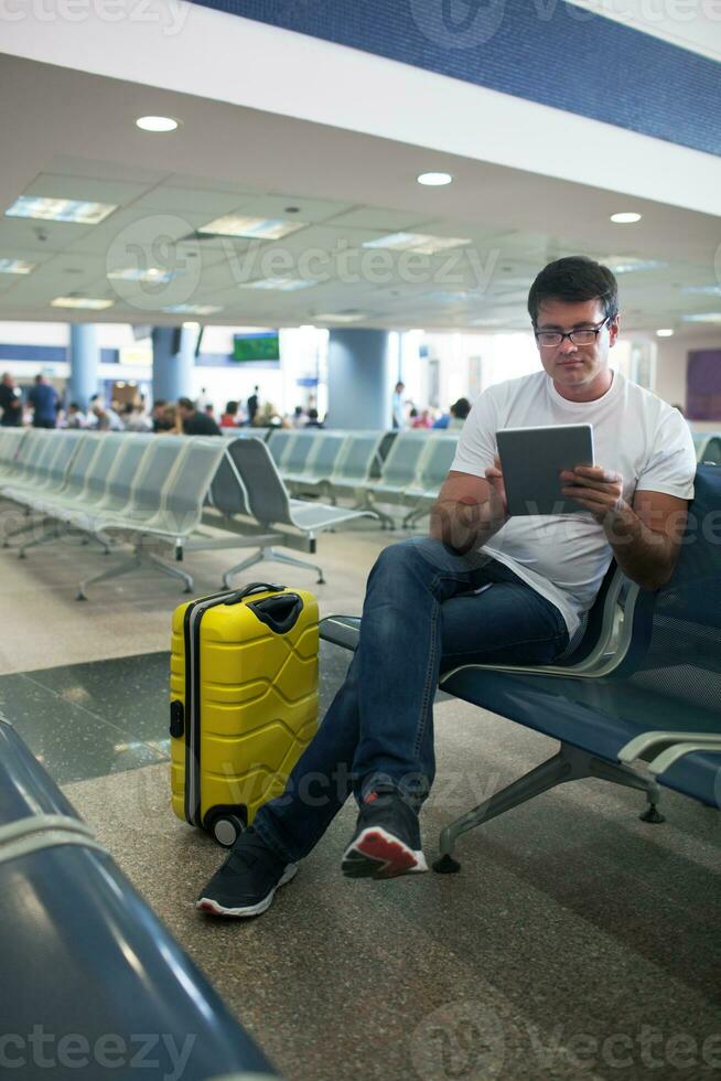 Jeune homme en utilisant toucher tampon dans le aéroport salon photo