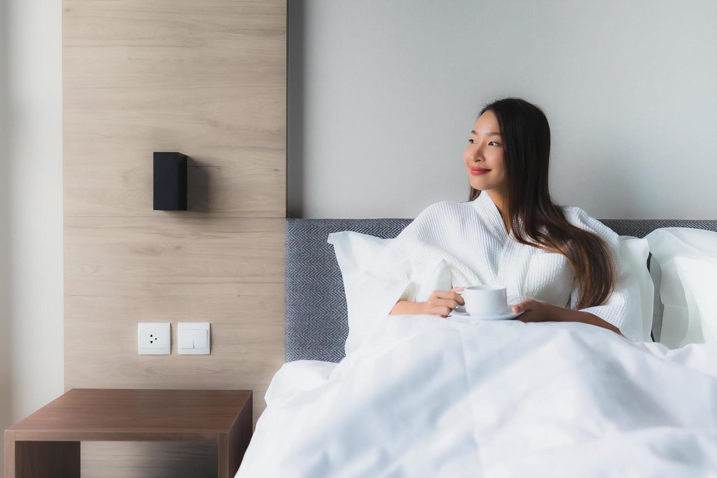 Portrait de belles jeunes femmes asiatiques avec une tasse de café sur le lit photo