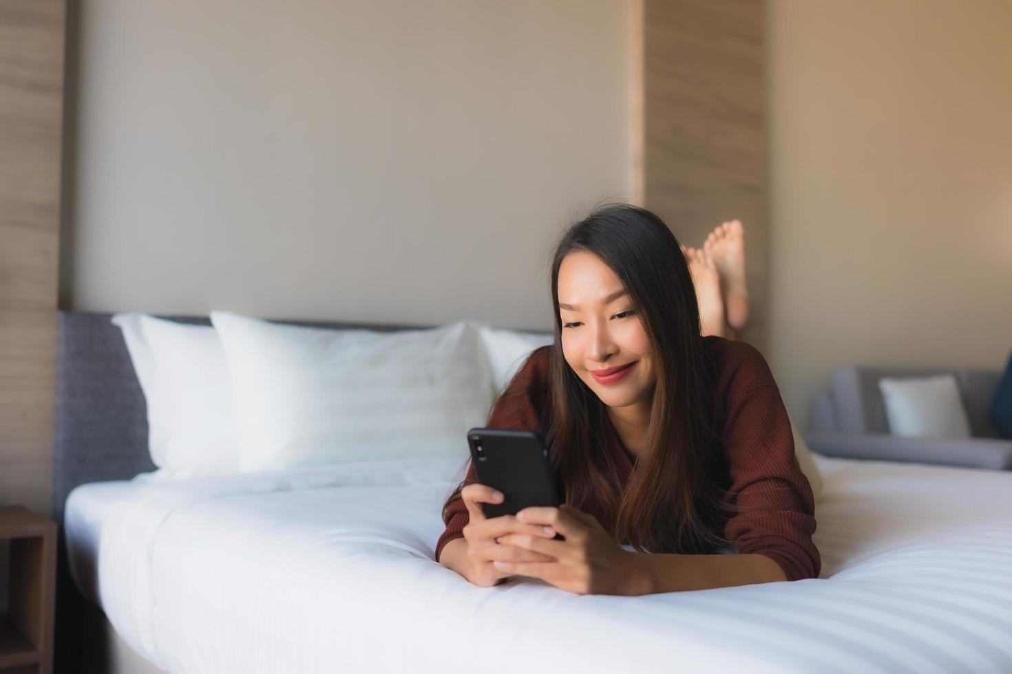 Portrait de belles jeunes femmes asiatiques utilisant un téléphone portable sur le lit photo