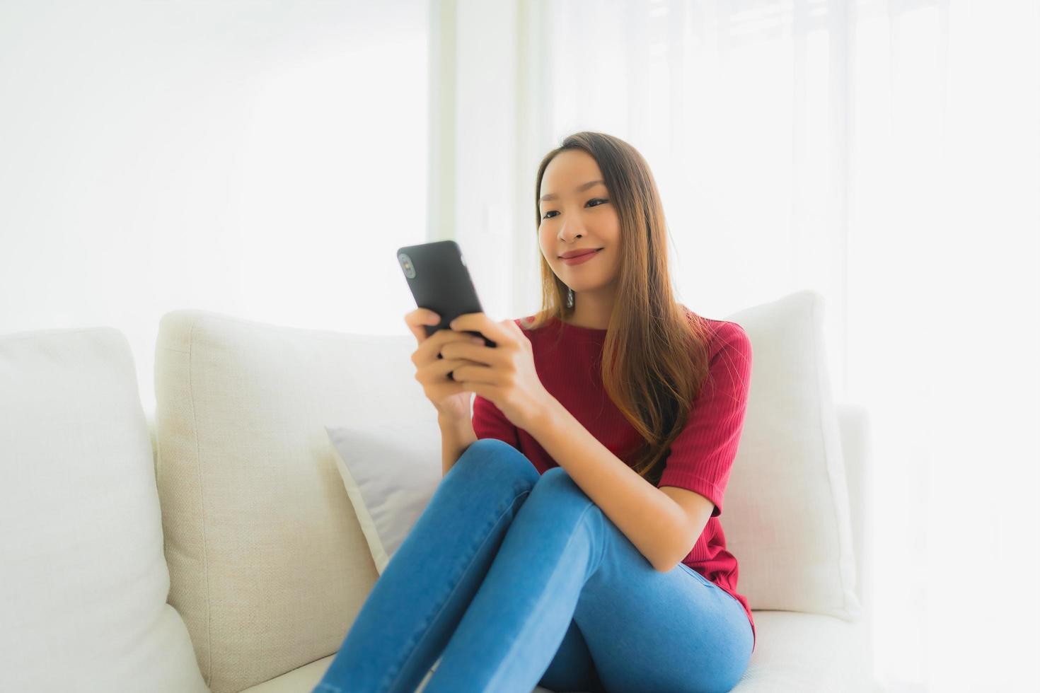 portrait de belles jeunes femmes asiatiques utilisant un téléphone portable ou intelligent sur un canapé photo