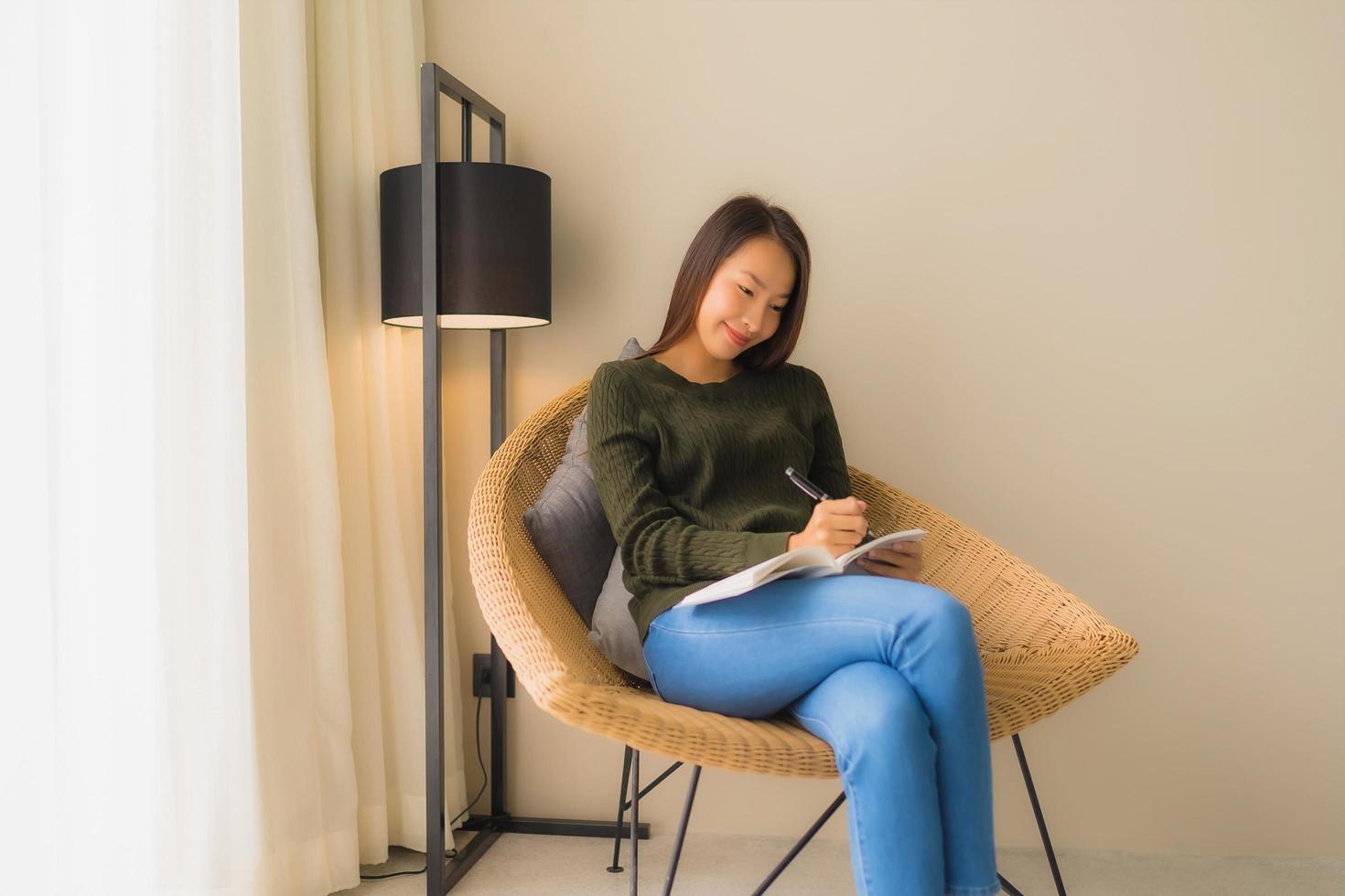 Portrait de belles jeunes femmes asiatiques lisant un livre et assis sur une chaise de canapé photo