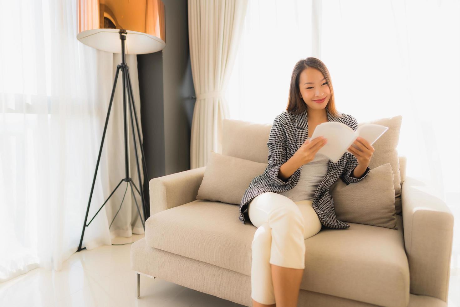 Portrait de belles jeunes femmes asiatiques lisant un livre et assis sur une chaise de canapé photo